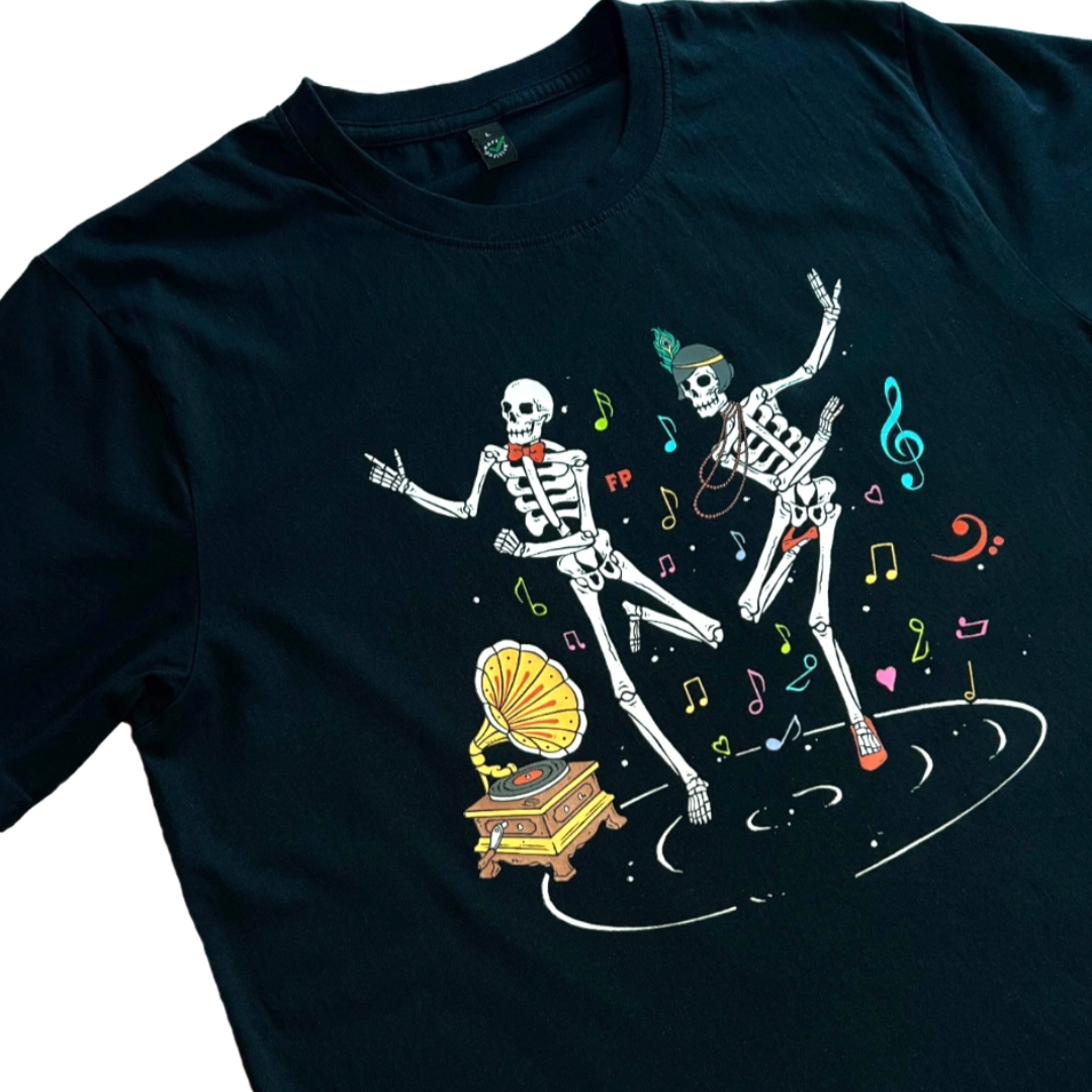closeup of a black unisex t-shirt with two skeletons dancing the Charleston next to a gramophone. different coloured musical notes are floating around them