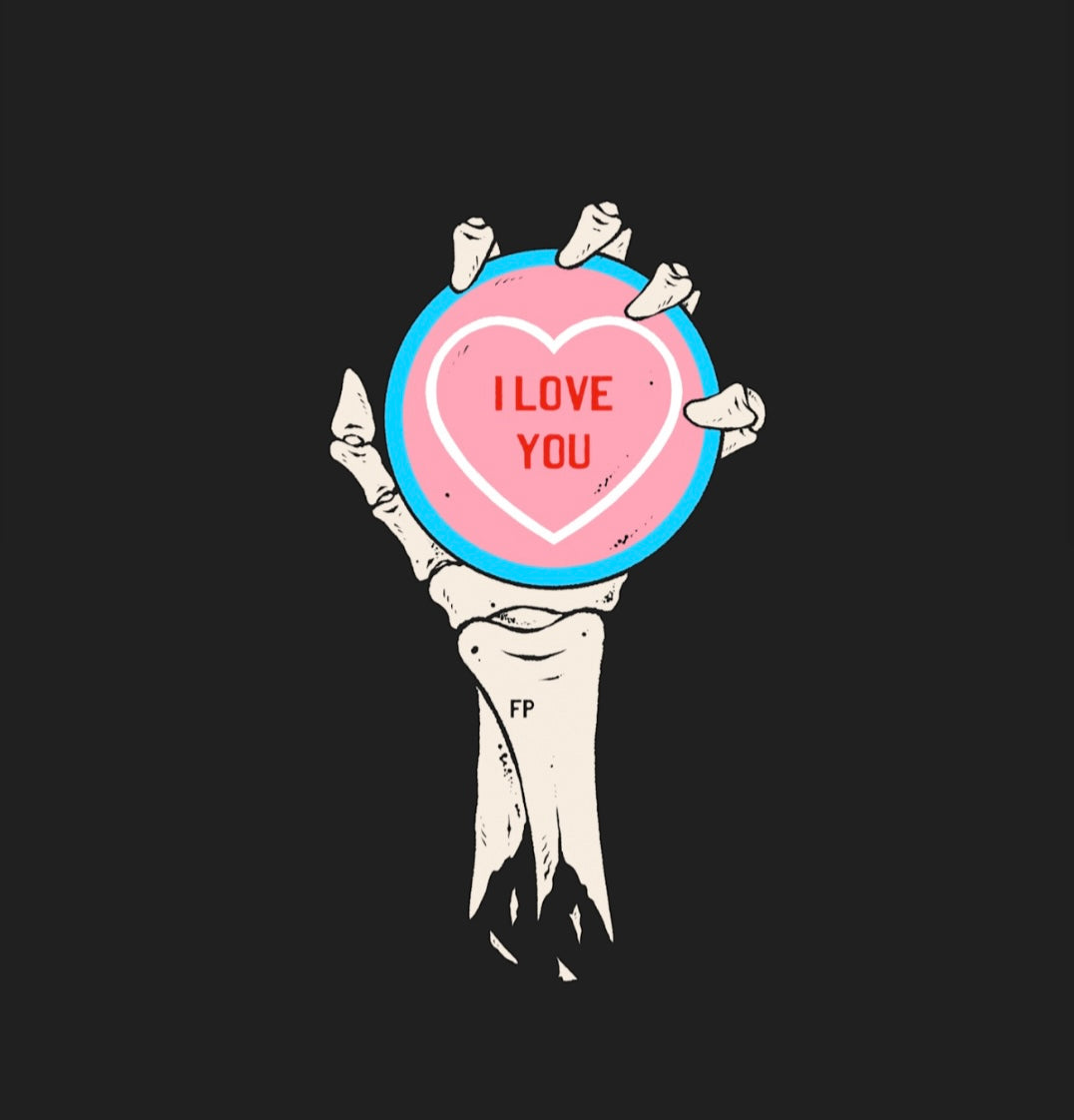 artwork of a skeleton hand and forearm holding an oversized love heart candy. I Love You is written on the candy. the colours of the candy are the same as the transgender flag